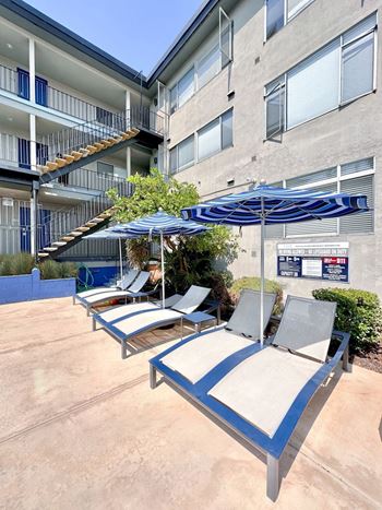 Poolside lounge chairs with umbrellas and greenery